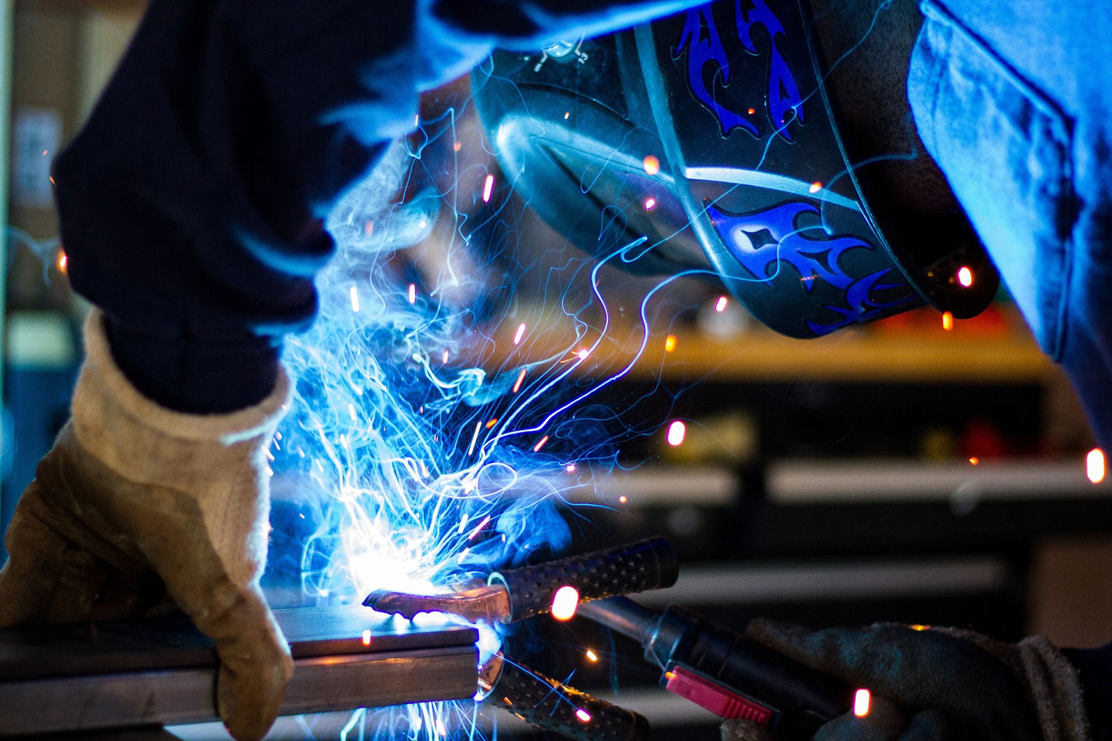 Welder fabricating metal with sparks